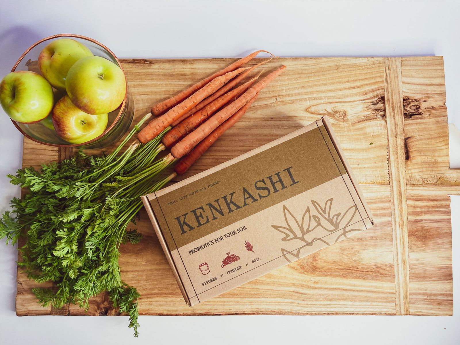 Kenkashi box of inoculated microbial kenaf in box on a wood cutting board with farm fresh carrots and apples