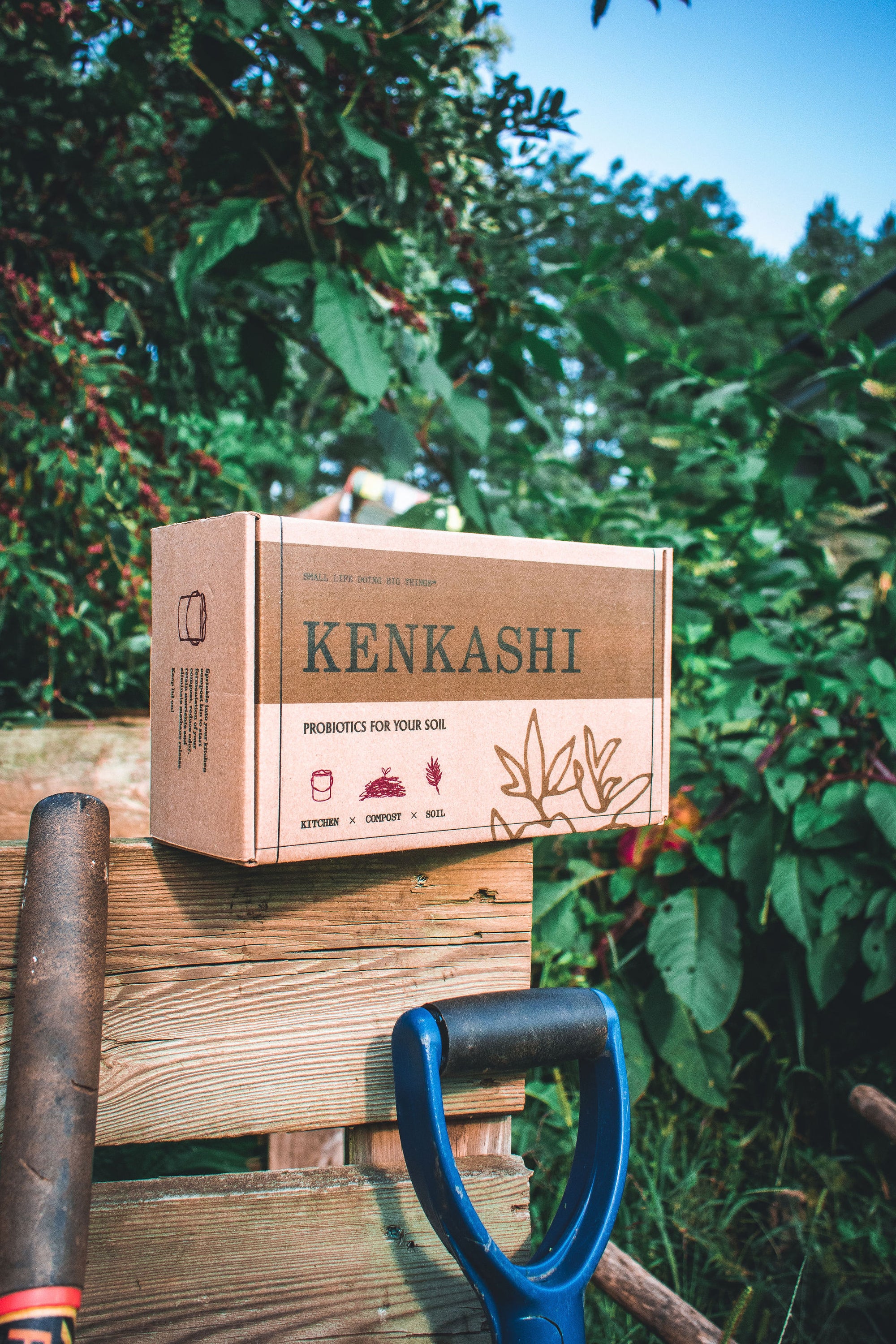 Kenkashi box of bokashi inoculated microbial hemp kenaf in front of plants with tools 